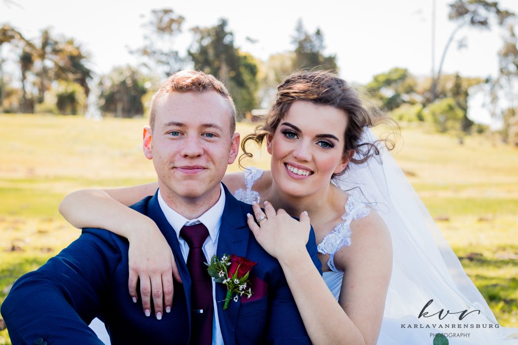 couple in wedding attire sitting out in nature